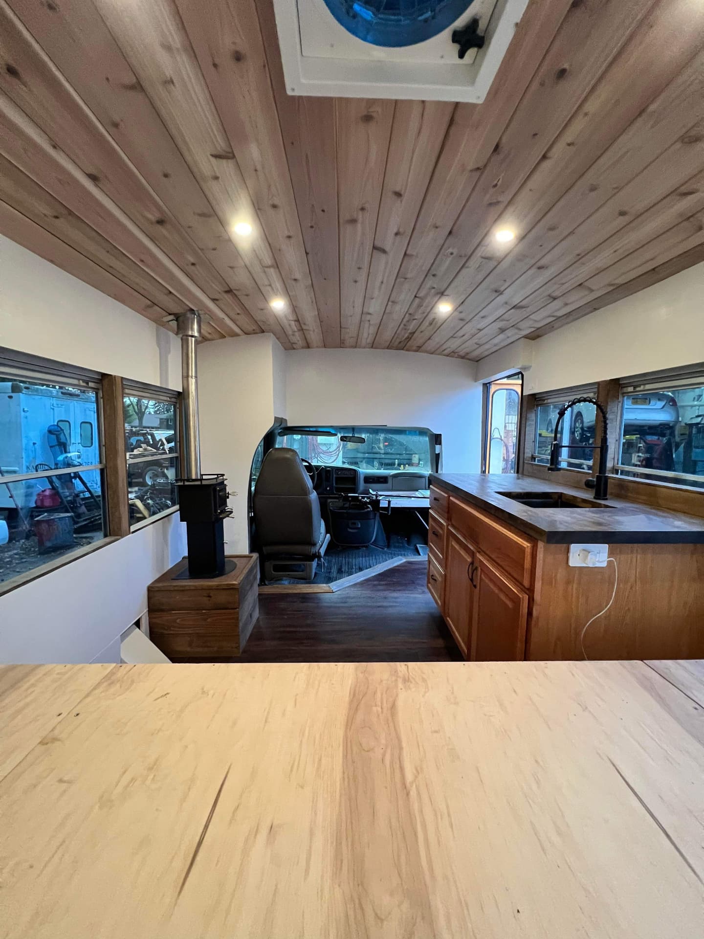 Skoolie conversion with wood plank ceiling, wood stove and full kitchen island