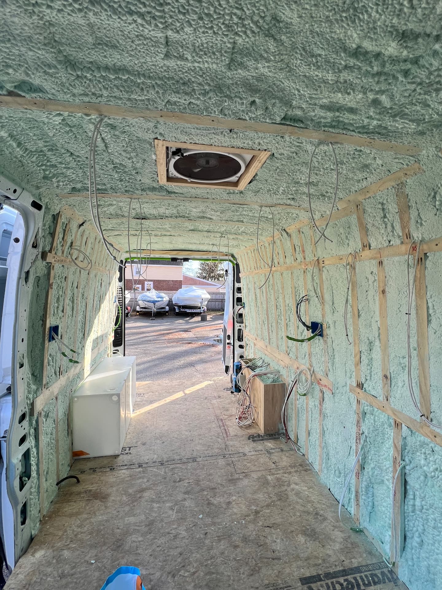 Camper van ceiling with spray foam insulation and a roof fan roughed in