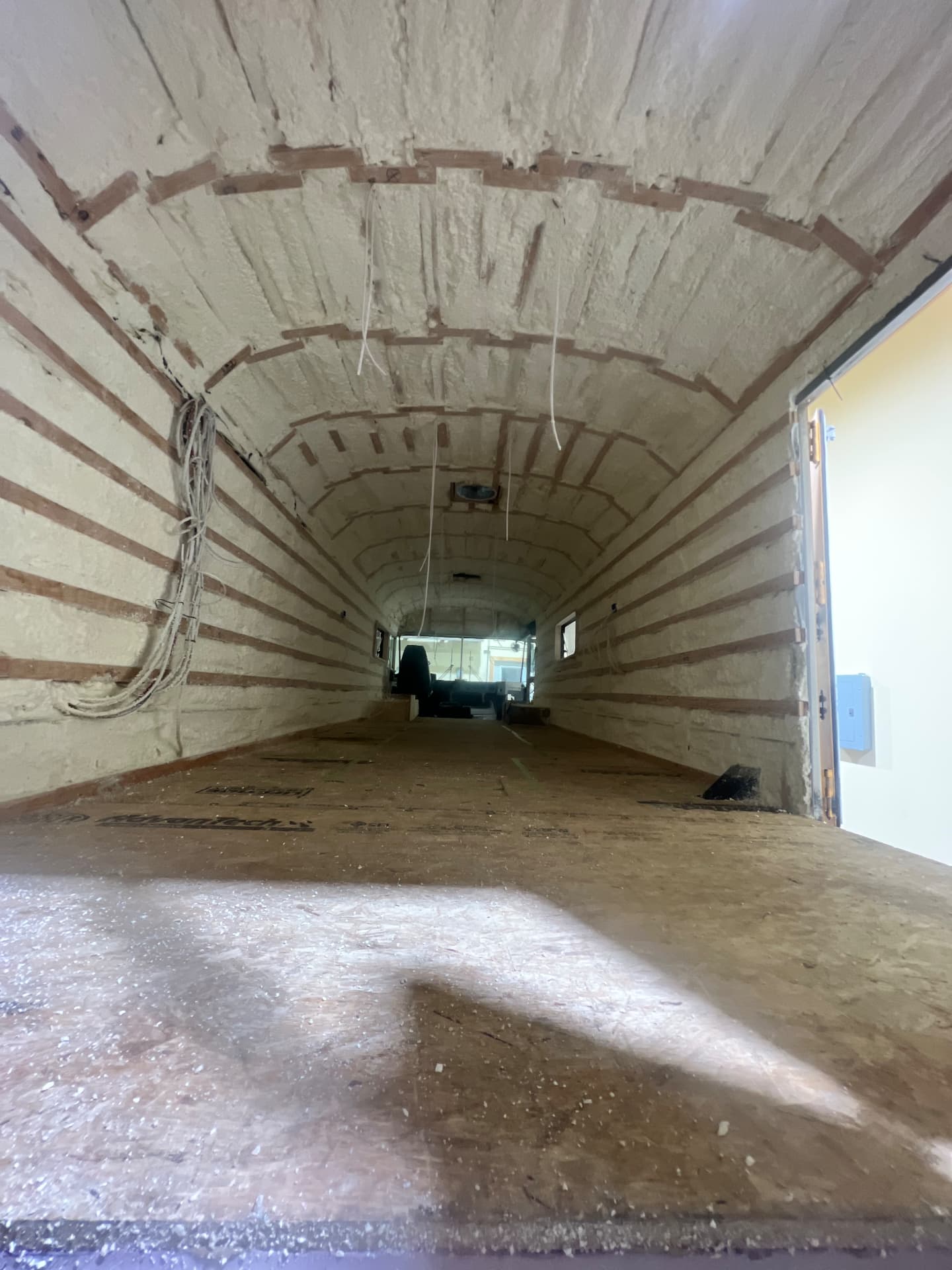 Skoolie shell with spray foam insulation and wiring runs during a custom conversion build