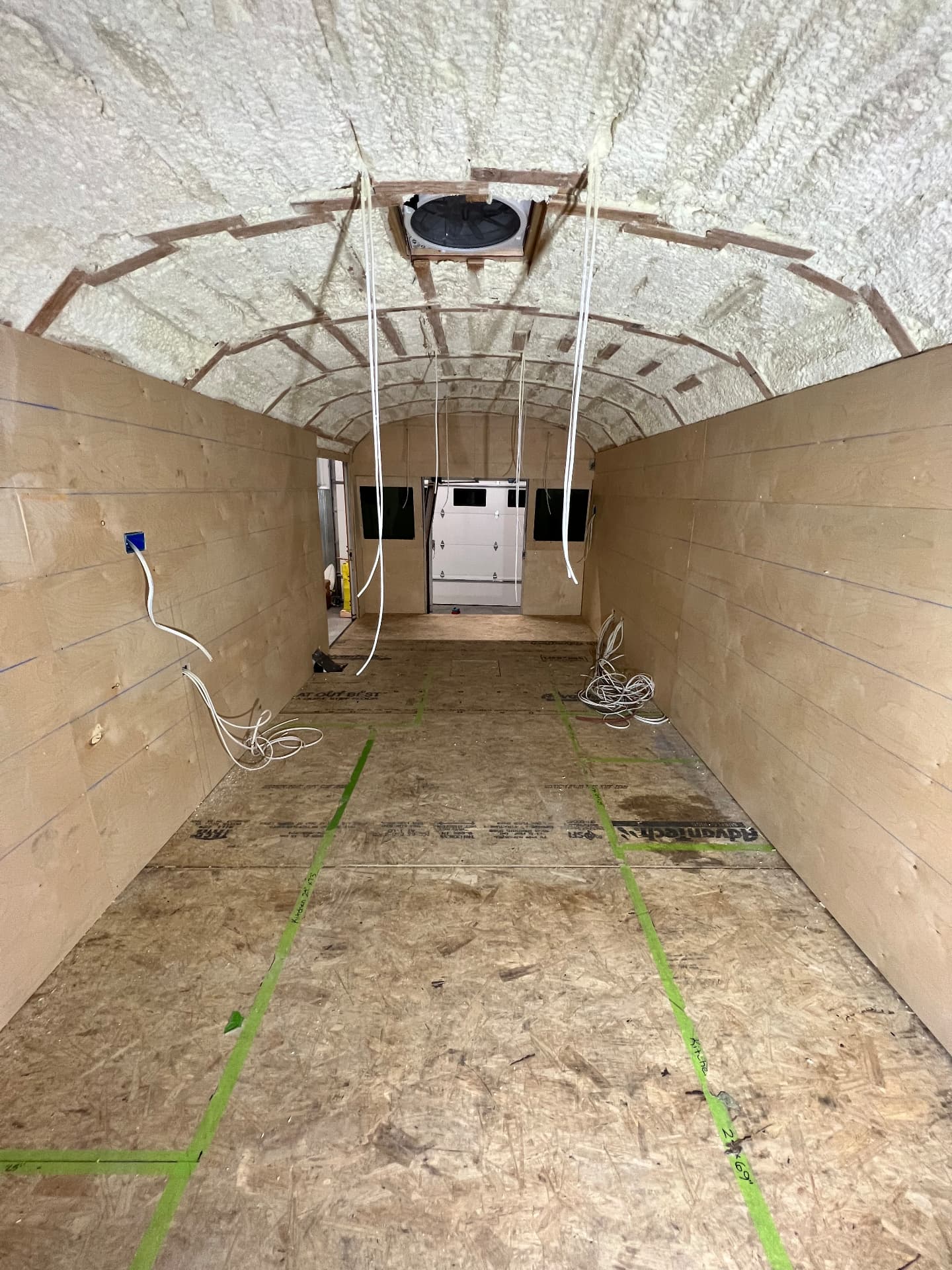 Skoolie interior lined with plywood wall panels with wiring routed to planned outlet locations